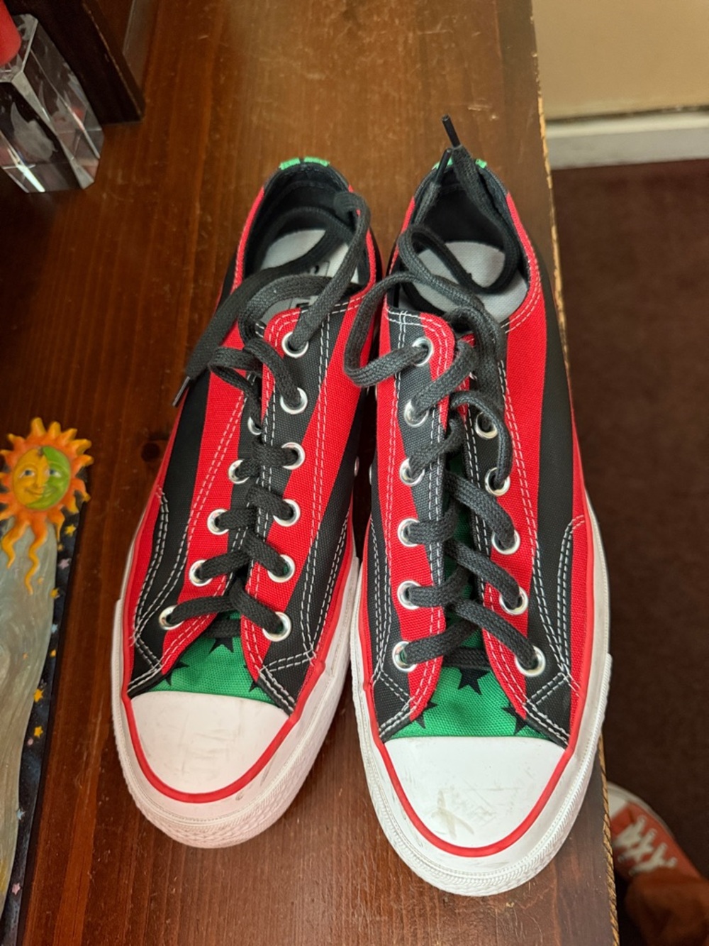 Women’s or men’s low top Converse shoes. Red and black strips with green stars